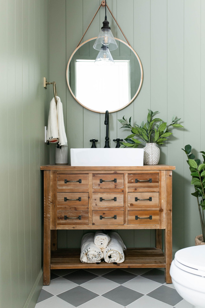 Design ideas for a country powder room in Phoenix with furniture-like cabinets, medium wood cabinets, green walls, a vessel sink, grey floor and brown benchtops.