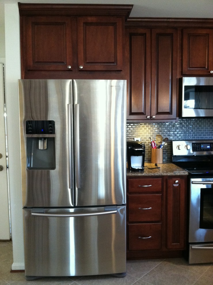 Example of a large transitional u-shaped ceramic tile and beige floor enclosed kitchen design with raised-panel cabinets, dark wood cabinets, granite countertops, blue backsplash, ceramic backsplash, stainless steel appliances, an undermount sink and a peninsula
