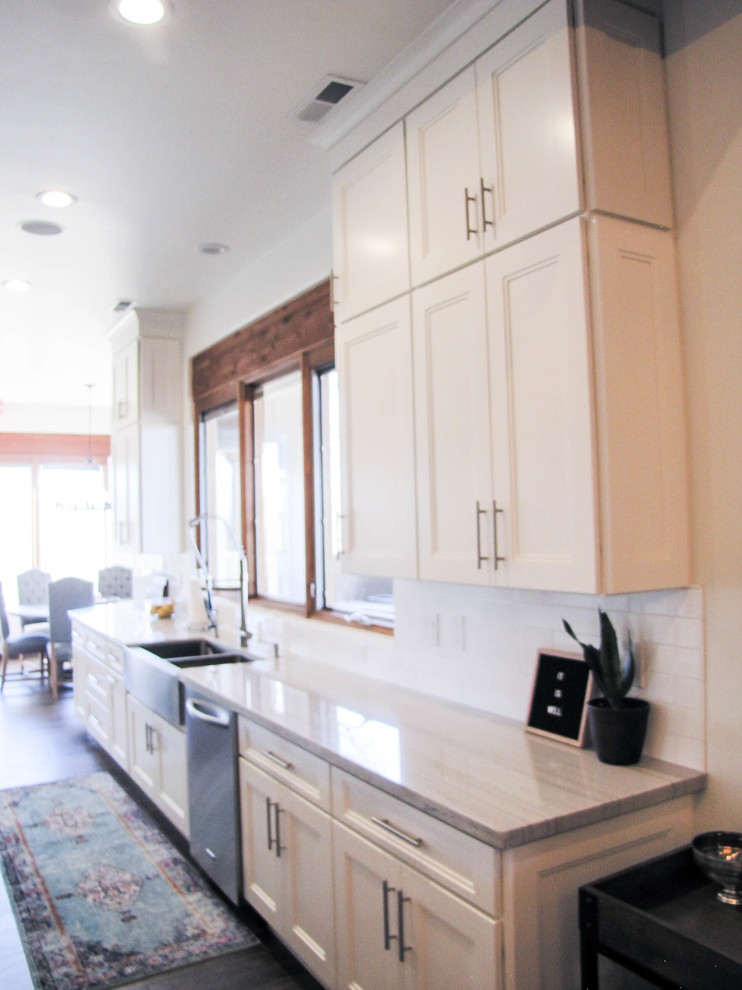 Kitchen - large transitional porcelain tile and brown floor kitchen idea in Phoenix with a farmhouse sink, white cabinets, white backsplash, subway tile backsplash, stainless steel appliances and an island