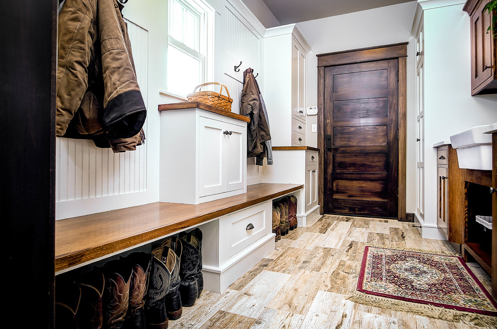 Photo of a mid-sized country mudroom in Other with grey walls, light hardwood floors, a single front door and a dark wood front door.