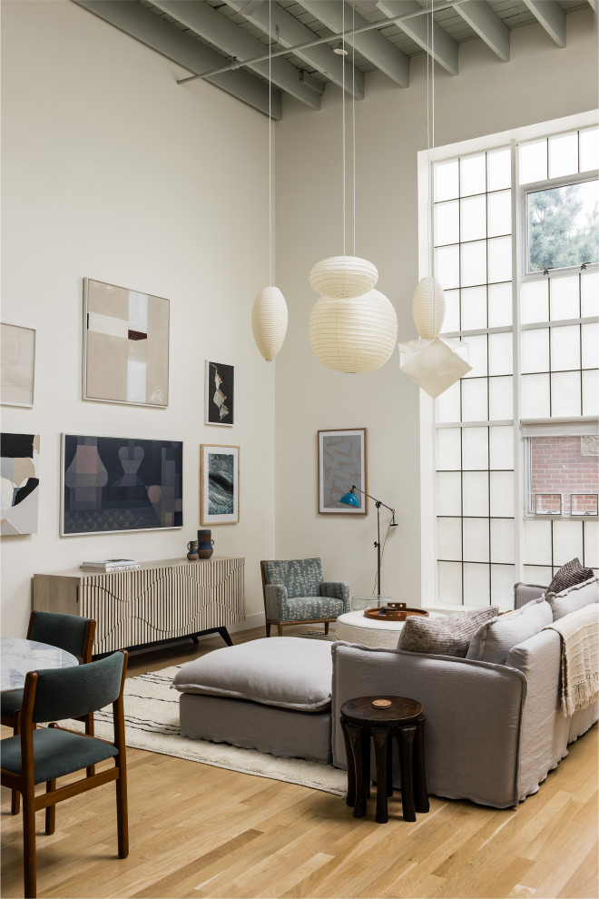 Immagine di un soggiorno industriale con pareti beige, parquet chiaro, TV a parete, pavimento beige e travi a vista
