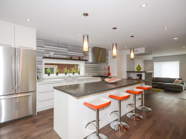 Inspiration for a mid-sized modern single-wall dark wood floor eat-in kitchen remodel in Toronto with a double-bowl sink, flat-panel cabinets, white cabinets, quartz countertops, white backsplash, marble backsplash, stainless steel appliances and an island
