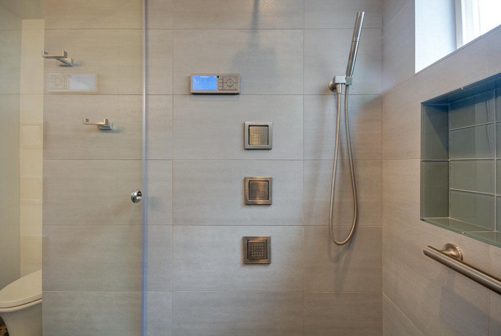This is an example of a small contemporary 3/4 bathroom in Seattle with a curbless shower, a wall-mount toilet, gray tile, white walls, pebble tile floors, multi-coloured floor, an open shower and grey benchtops.