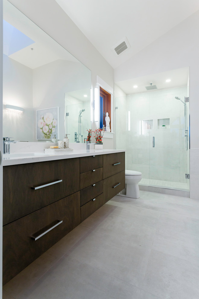 Large contemporary master bathroom in Vancouver with flat-panel cabinets, brown cabinets, a freestanding tub, an alcove shower, a two-piece toilet, gray tile, porcelain tile, white walls, porcelain floors, an undermount sink, engineered quartz benchtops, grey floor and a hinged shower door.