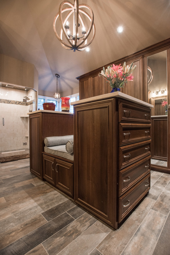 Design ideas for a large traditional gender-neutral walk-in wardrobe in Denver with raised-panel cabinets, medium wood cabinets, plywood floors and brown floor.