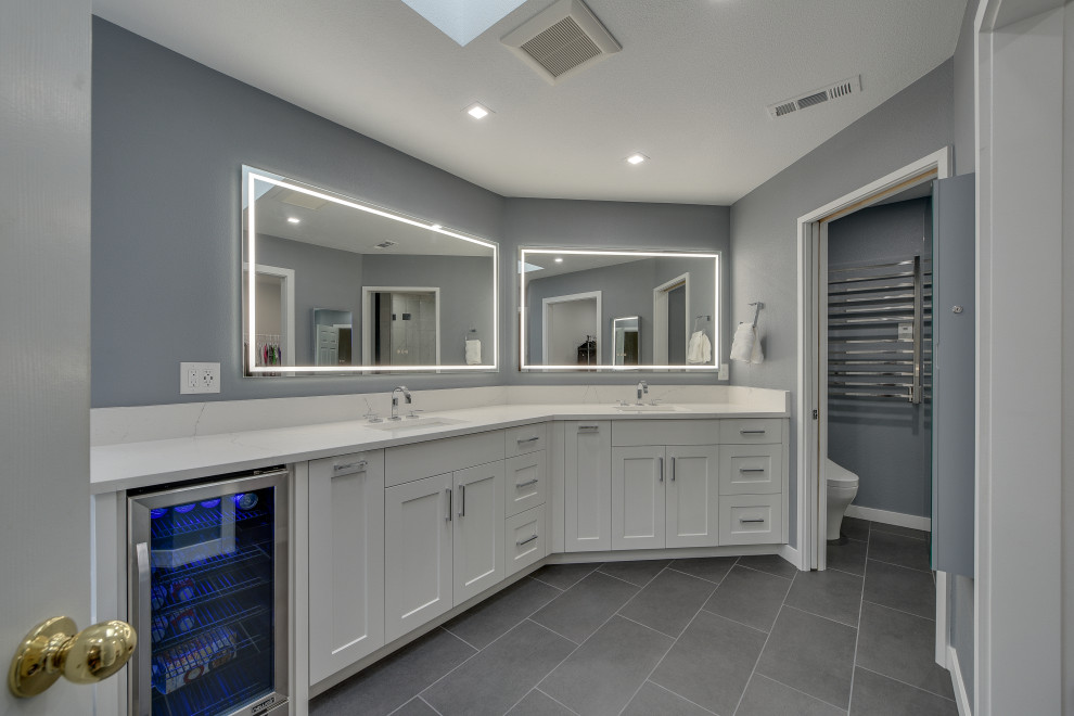 Photo of a mid-sized modern master bathroom in Portland with flat-panel cabinets, white cabinets, a freestanding tub, a drop-in sink, grey floor, white benchtops, an enclosed toilet, a double vanity, a double shower, a two-piece toilet, grey walls, porcelain floors, quartzite benchtops and a built-in vanity.