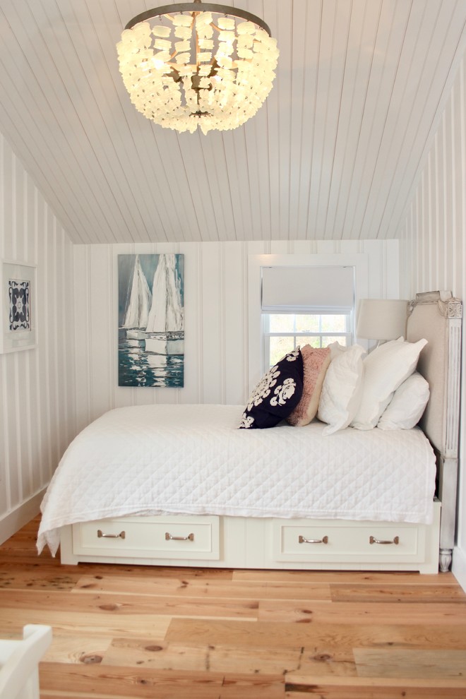 This is an example of a beach style bedroom in Boston with white walls, medium hardwood floors and brown floor.