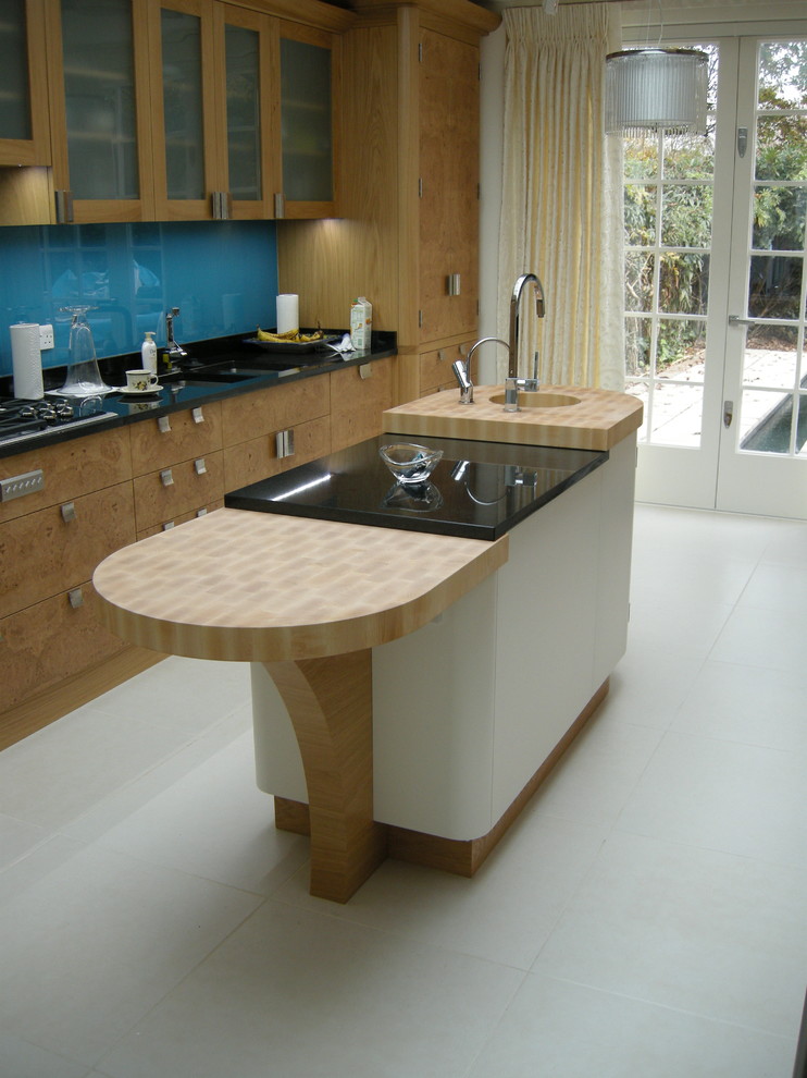 Inspiration for a large contemporary galley eat-in kitchen in Other with an integrated sink, flat-panel cabinets, medium wood cabinets, granite benchtops, blue splashback, glass tile splashback, panelled appliances, ceramic floors and with island.