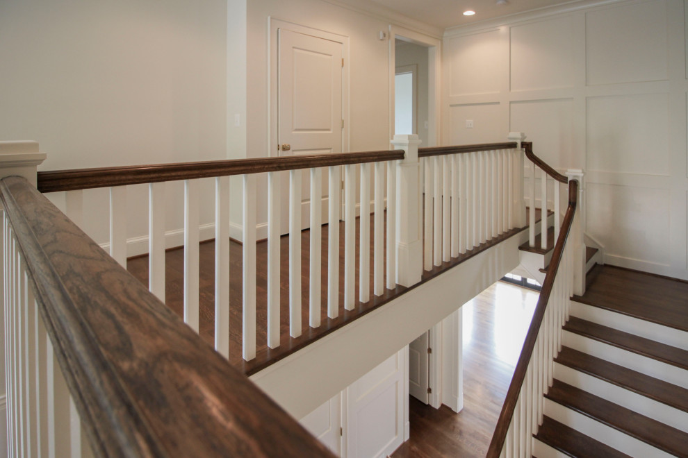 Design ideas for a large transitional wood u-shaped staircase in DC Metro with wood risers, wood railing and decorative wall panelling.