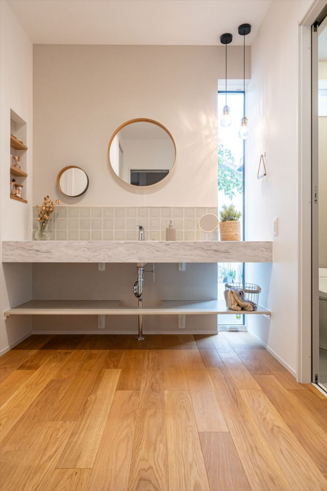 Inspiration for a mid-sized contemporary powder room in Other with open cabinets, white cabinets, a bidet, gray tile, mosaic tile, white walls, grey benchtops and a built-in vanity.