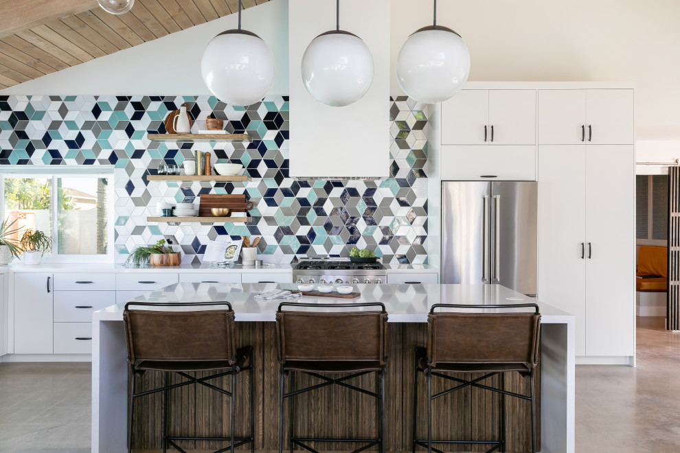 Mid-sized mid-century modern l-shaped concrete floor, gray floor and exposed beam eat-in kitchen photo in Orange County with an undermount sink, flat-panel cabinets, white cabinets, quartz countertops, blue backsplash, ceramic backsplash, stainless steel appliances, an island and white countertops