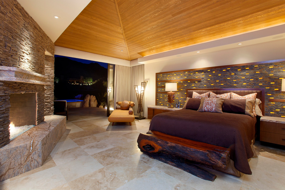 This is an example of an expansive contemporary master bedroom in Other with brown walls, travertine floors, a standard fireplace, a stone fireplace surround and beige floor.