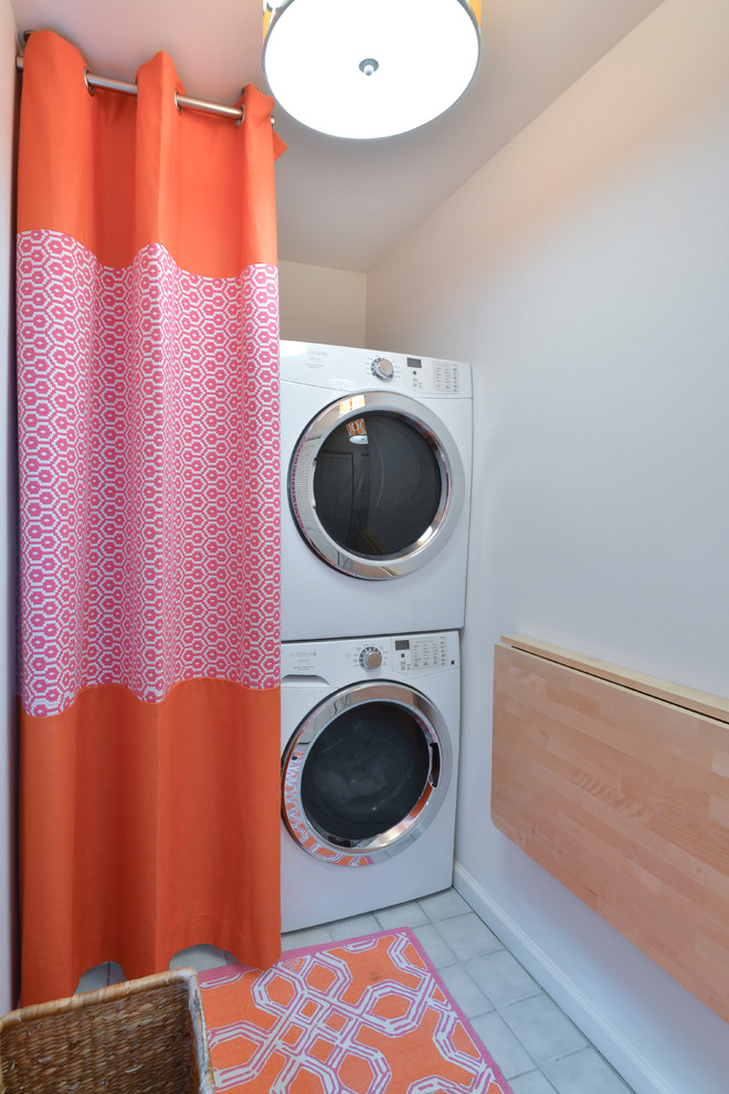 Inspiration for a beach style single-wall laundry room in Charleston with white walls and a stacked washer and dryer.