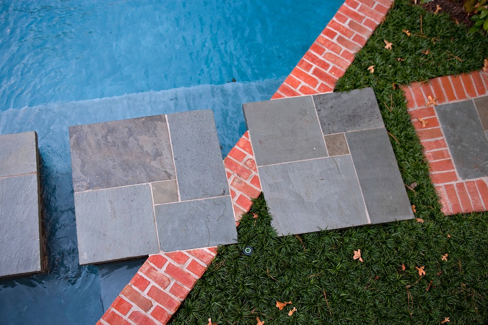This is an example of a small eclectic backyard custom-shaped natural pool in Houston with natural stone pavers.