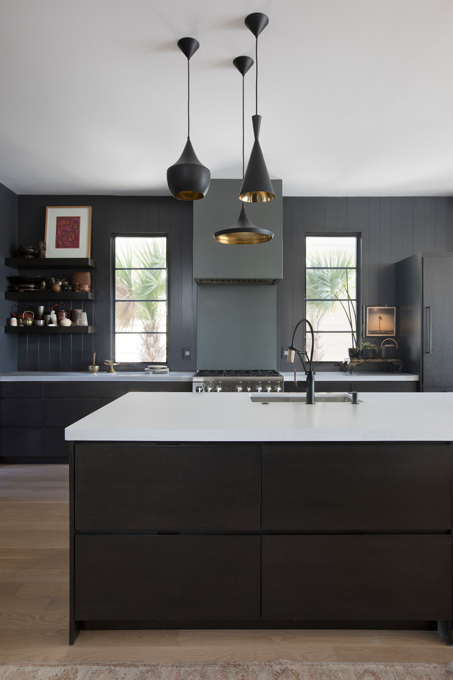 Inspiration for a contemporary eat-in kitchen in Charleston with an undermount sink, flat-panel cabinets, black cabinets, marble benchtops, metallic splashback, panelled appliances, light hardwood floors, with island and white benchtop.