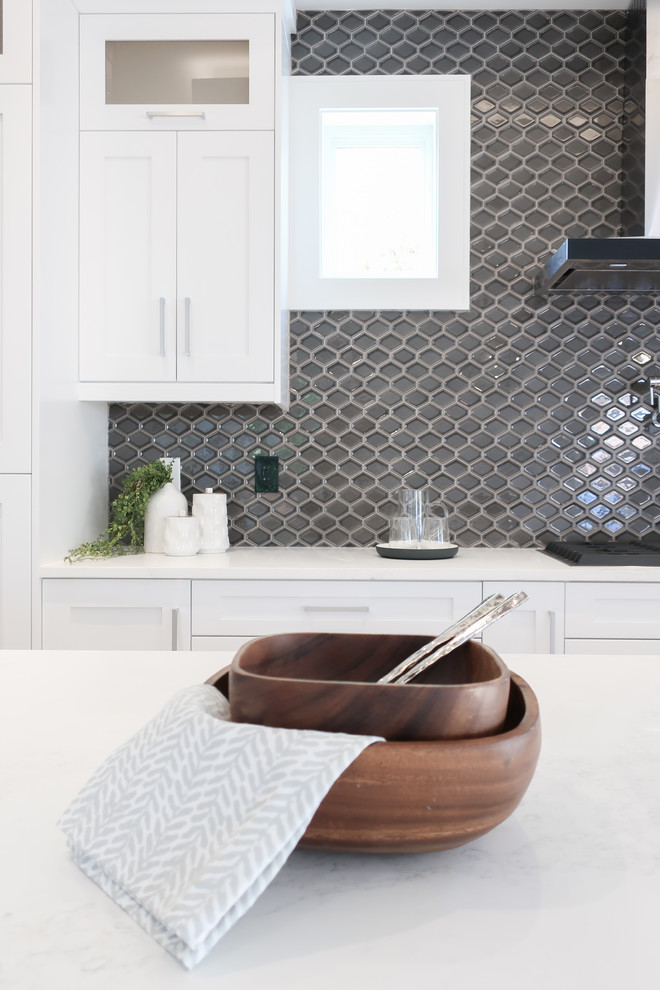 Example of a transitional kitchen design in Vancouver with shaker cabinets, white cabinets, quartz countertops, gray backsplash, mosaic tile backsplash, an island and white countertops