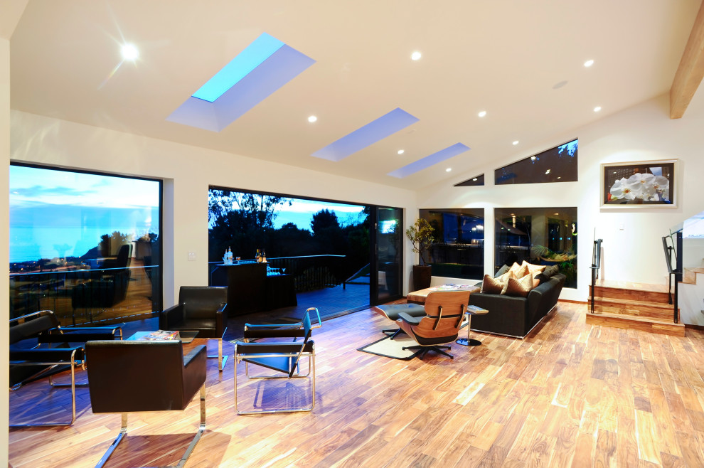 Photo of a large contemporary open concept living room in Los Angeles with grey walls, light hardwood floors, beige floor and coffered.