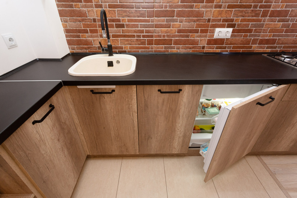 Photo of a small country l-shaped separate kitchen in Other with raised-panel cabinets, black cabinets, wood benchtops, brown splashback, brick splashback, no island, brown floor and black benchtop.