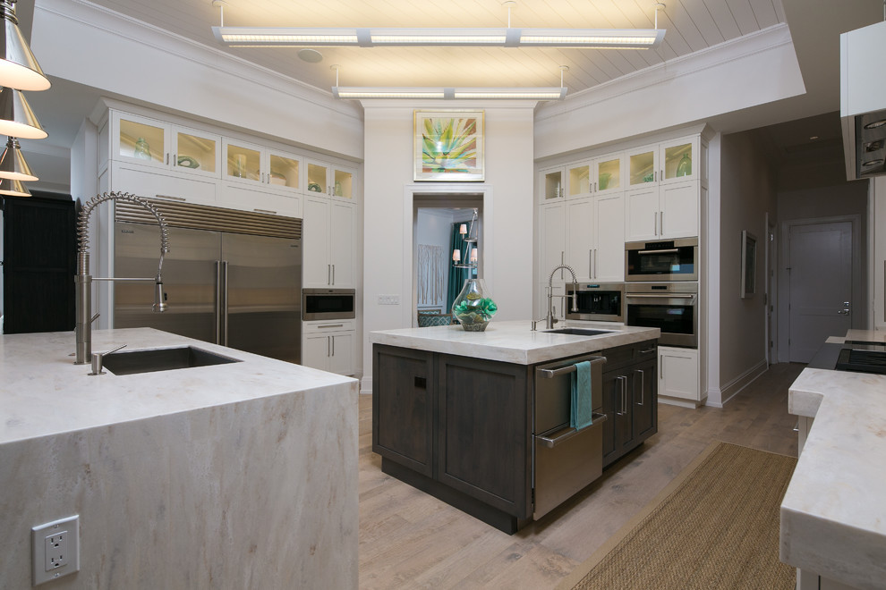 Example of a large transitional u-shaped light wood floor eat-in kitchen design in Miami with an undermount sink, shaker cabinets, white cabinets, marble countertops, stainless steel appliances and an island