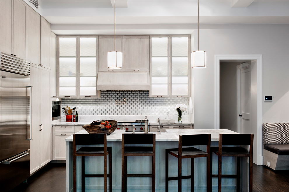Photo of a transitional eat-in kitchen in New York with glass-front cabinets, light wood cabinets, white splashback, subway tile splashback, stainless steel appliances, dark hardwood floors and with island.