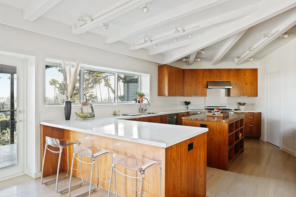 Design ideas for a large midcentury u-shaped open plan kitchen in Los Angeles with a double-bowl sink, medium wood cabinets, wood benchtops, white splashback, stainless steel appliances, light hardwood floors, with island, beige floor and white benchtop.