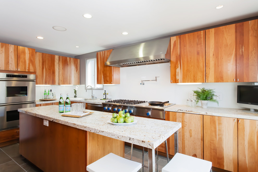 Photo of a contemporary kitchen in San Francisco with limestone benchtops, stainless steel appliances, flat-panel cabinets and white splashback.