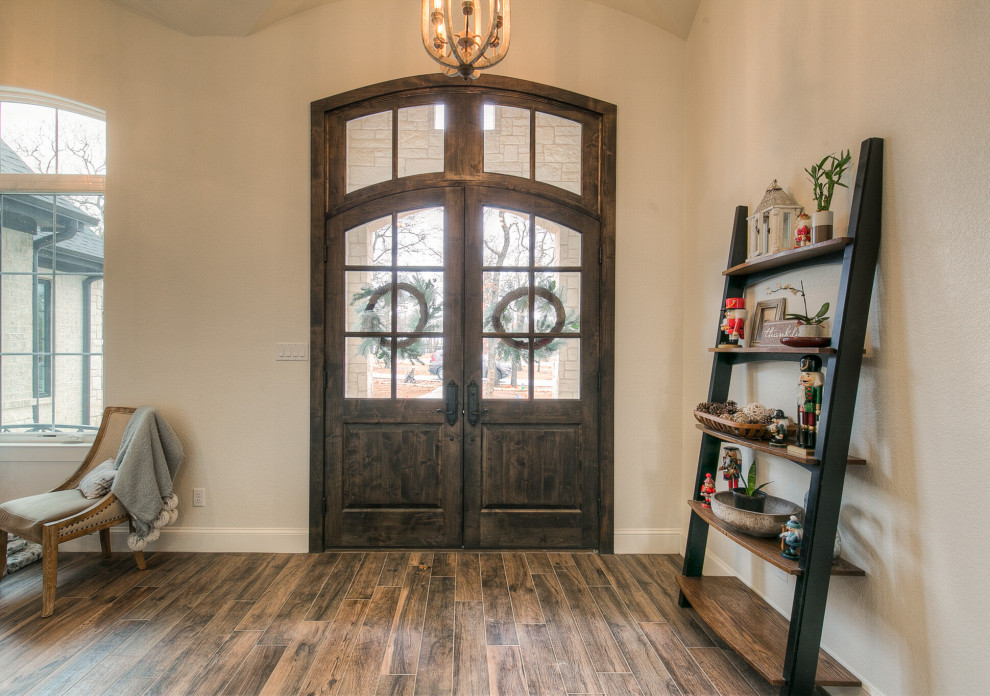 ダラスにあるシャビーシック調のおしゃれな玄関 (白い壁、磁器タイルの床、濃色木目調のドア) の写真