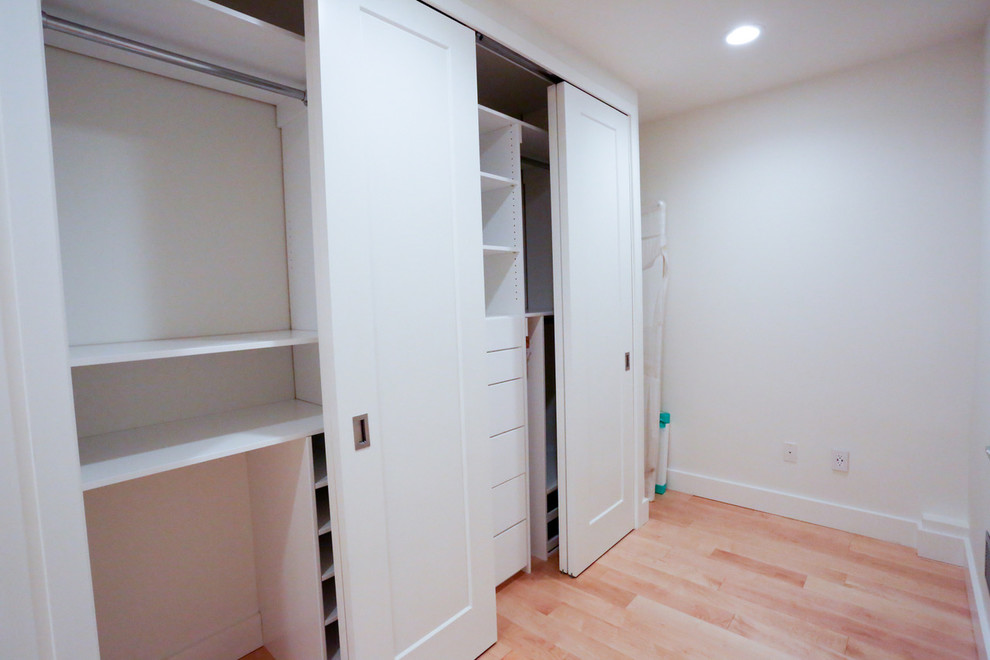Mid-sized contemporary gender-neutral built-in wardrobe in New York with open cabinets, white cabinets and light hardwood floors.