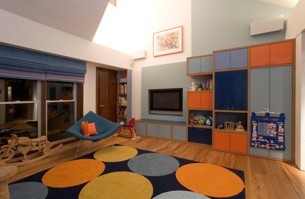 Design ideas for a large contemporary gender-neutral kids' playroom for kids 4-10 years old in London with multi-coloured walls and light hardwood floors.