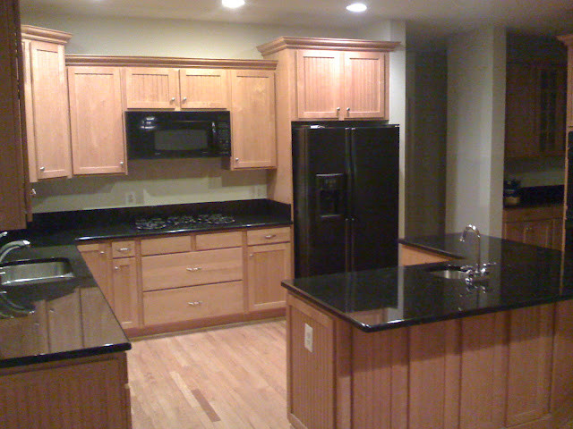 Example of a transitional kitchen design in DC Metro with beaded inset cabinets, medium tone wood cabinets, granite countertops, black appliances and an island