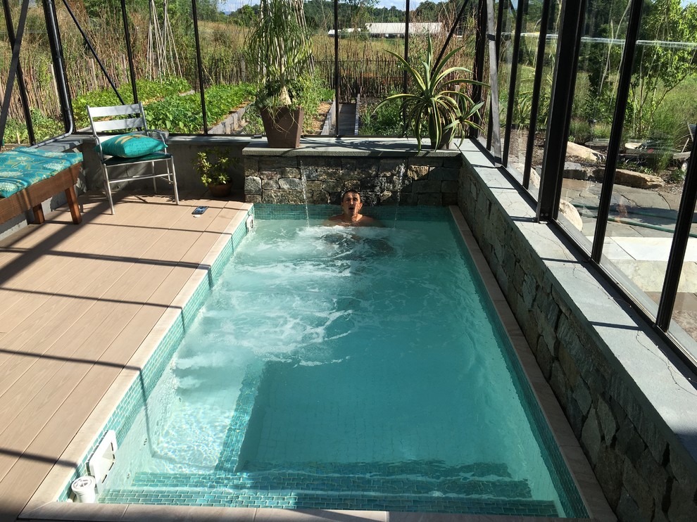 Small modern backyard rectangular lap pool in Burlington with a water feature and decking.