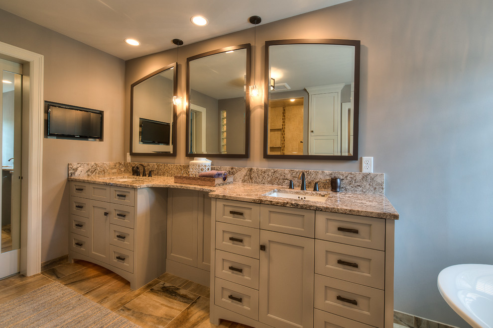 Photo of a large transitional master bathroom in Minneapolis with an undermount sink, recessed-panel cabinets, grey cabinets, granite benchtops, a freestanding tub, a one-piece toilet, grey walls, ceramic floors, an open shower, beige tile and ceramic tile.