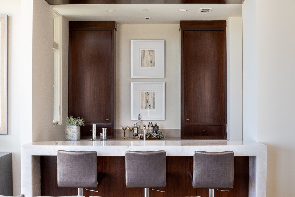 Photo of a contemporary seated home bar in Orange County with flat-panel cabinets, dark wood cabinets and white benchtop.