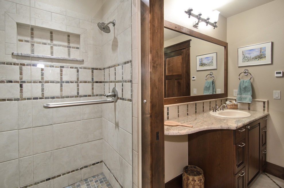 Traditional bathroom in Denver with a drop-in sink, raised-panel cabinets, dark wood cabinets, an alcove shower and beige tile.