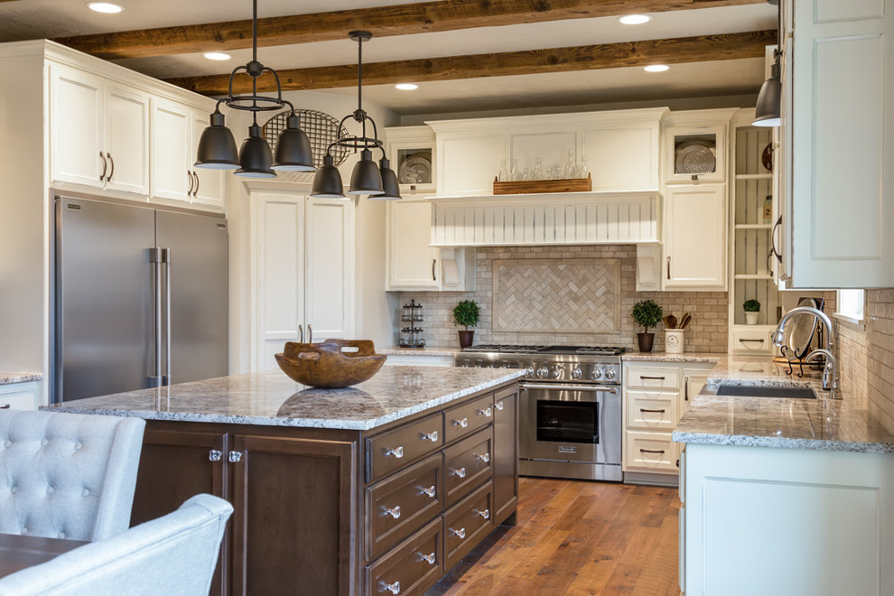 Large country u-shaped eat-in kitchen in Other with a farmhouse sink, recessed-panel cabinets, white cabinets, quartzite benchtops, beige splashback, stone tile splashback, stainless steel appliances, medium hardwood floors, with island and brown floor.