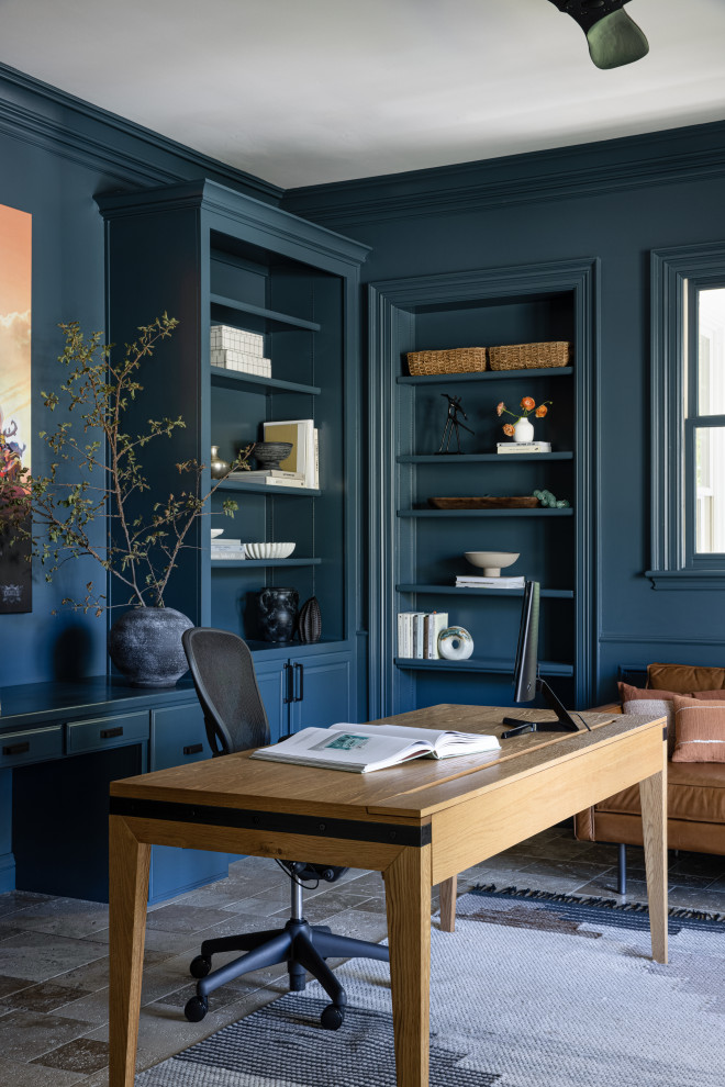 На фото: большой домашняя библиотека в стиле неоклассика (современная классика) с синими стенами, полом из травертина и отдельно стоящим рабочим столом с