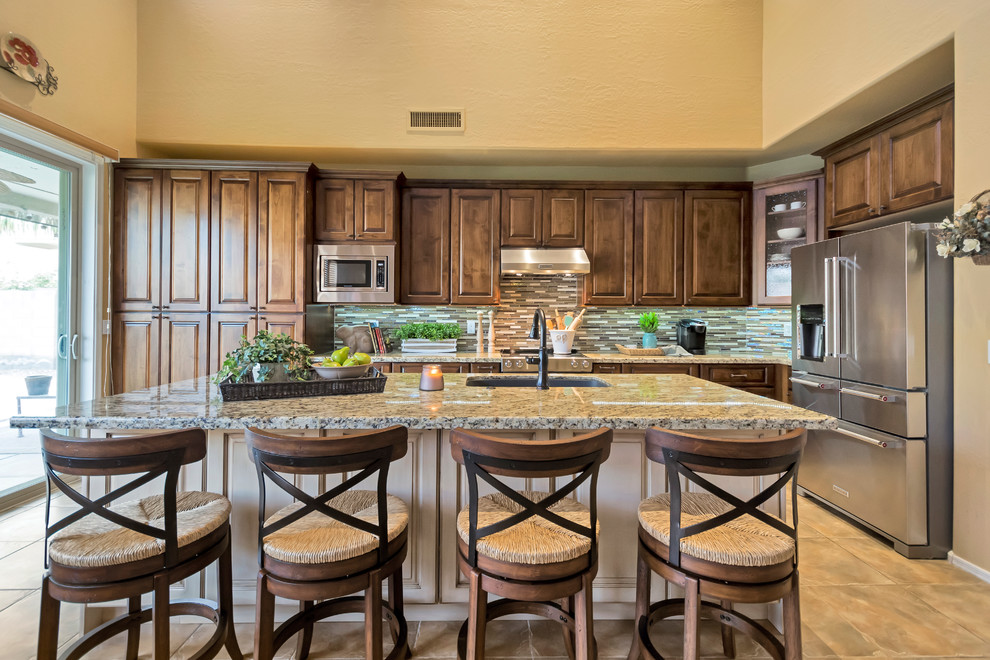 Inspiration for a mid-sized transitional galley eat-in kitchen remodel in Phoenix with an undermount sink, raised-panel cabinets, medium tone wood cabinets, granite countertops, multicolored backsplash, glass tile backsplash, stainless steel appliances and an island