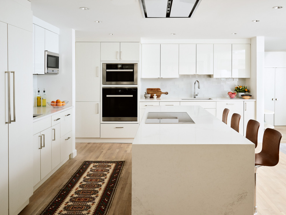 Mid-sized modern l-shaped separate kitchen in Boston with an undermount sink, flat-panel cabinets, white cabinets, quartz benchtops, stainless steel appliances, medium hardwood floors, with island and white benchtop.