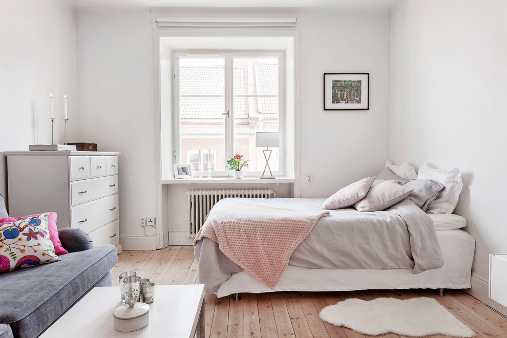Large scandinavian master bedroom in Stockholm with white walls, light hardwood floors and no fireplace.