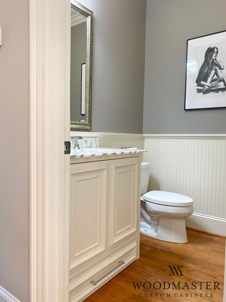 Aménagement d'un petit WC et toilettes campagne avec un placard en trompe-l'oeil, des portes de placard blanches, WC à poser, un mur gris, un sol en bois brun, un lavabo intégré et meuble-lavabo encastré.