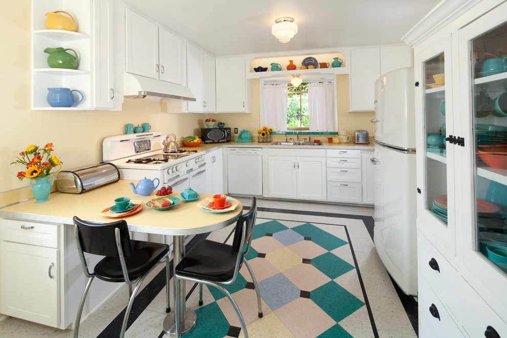 Inspiration for a mid-sized midcentury u-shaped kitchen in Santa Barbara with a double-bowl sink, shaker cabinets, white cabinets, laminate benchtops, white appliances, linoleum floors, with island, multi-coloured floor and white benchtop.
