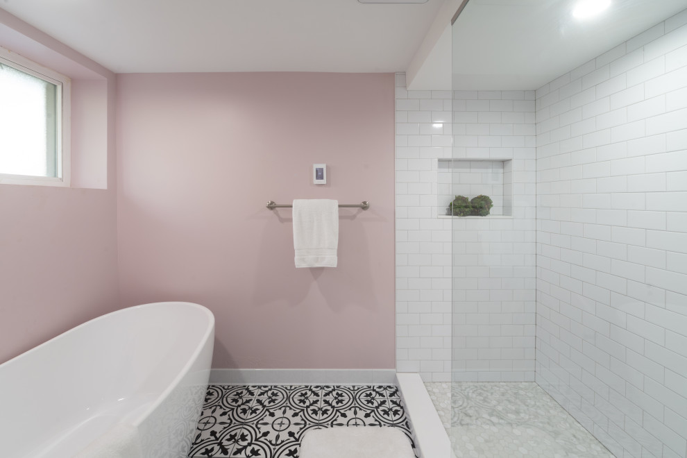 На фото: главный совмещенный санузел среднего размера с отдельно стоящей ванной, душем, унитазом-моноблоком, белой плиткой, плиткой кабанчик, розовыми стенами, полом из керамической плитки, столешницей из искусственного камня, разноцветным полом, открытым душем, белой столешницей, тумбой под одну раковину, напольной тумбой и обоями на стенах с