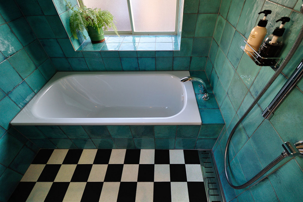 Photo of a mid-sized tropical master wet room bathroom in Tokyo with an alcove tub, blue tile, glass tile, porcelain floors, black floor and a hinged shower door.