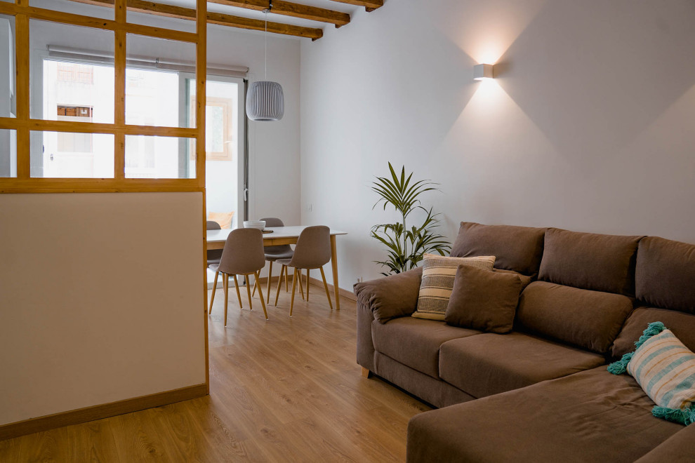 Mid-sized open concept medium tone wood floor, brown floor, exposed beam and brick wall living room photo in Barcelona with white walls and a wall-mounted tv
