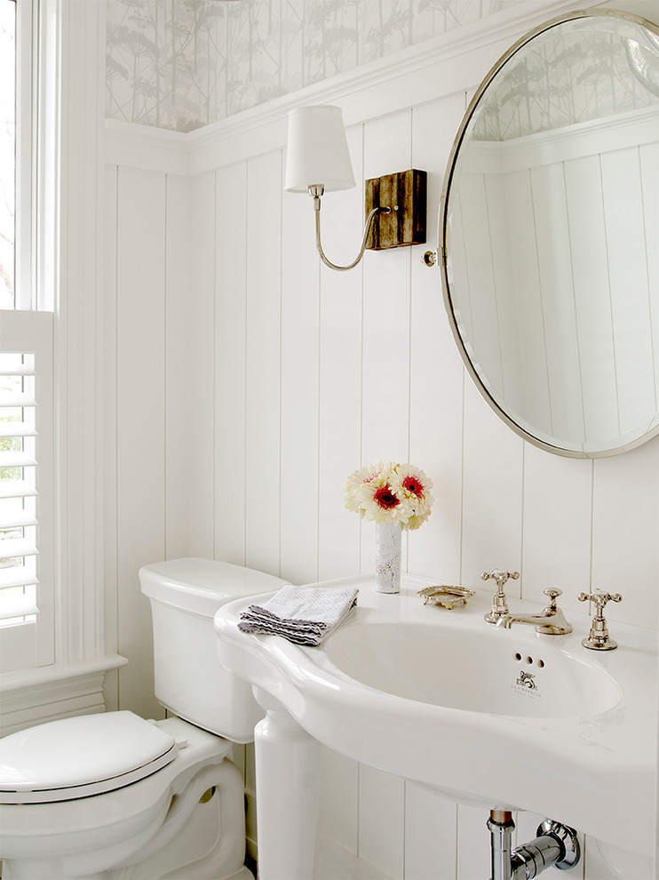 This is an example of a beach style powder room in New York with a wall-mount sink and white walls.