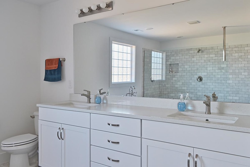 This is an example of a large modern master bathroom in Raleigh with an undermount sink, shaker cabinets, white cabinets, granite benchtops, a freestanding tub, a double shower, a two-piece toilet, gray tile, ceramic tile, white walls and ceramic floors.