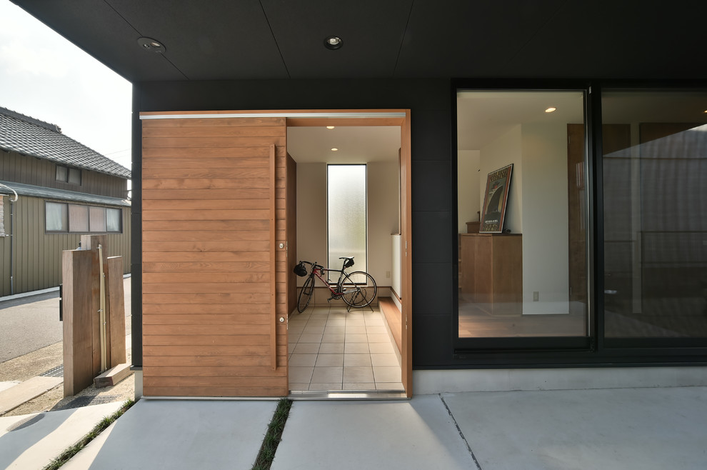 Photo of an asian entryway in Nagoya with black walls, a sliding front door, a light wood front door and grey floor.