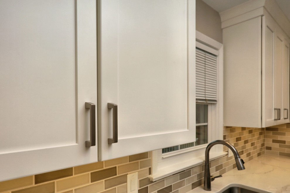 Example of a small transitional ceramic tile and beige floor kitchen design with a double-bowl sink, shaker cabinets, quartz countertops, beige backsplash, ceramic backsplash, stainless steel appliances and white countertops