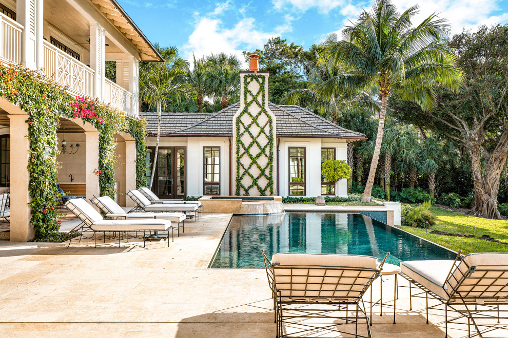 Ispirazione per un'ampia piscina a sfioro infinito tropicale rettangolare in cortile con pavimentazioni in pietra naturale