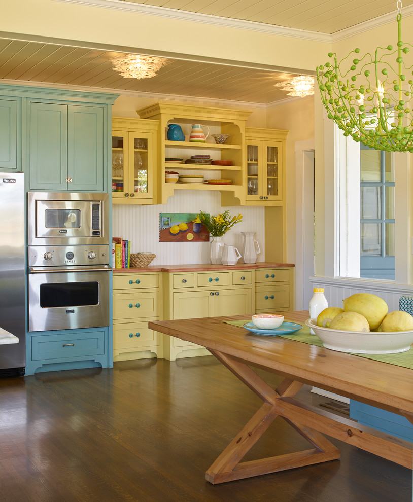 Design ideas for a country eat-in kitchen in San Francisco with yellow cabinets, wood benchtops, stainless steel appliances and dark hardwood floors.